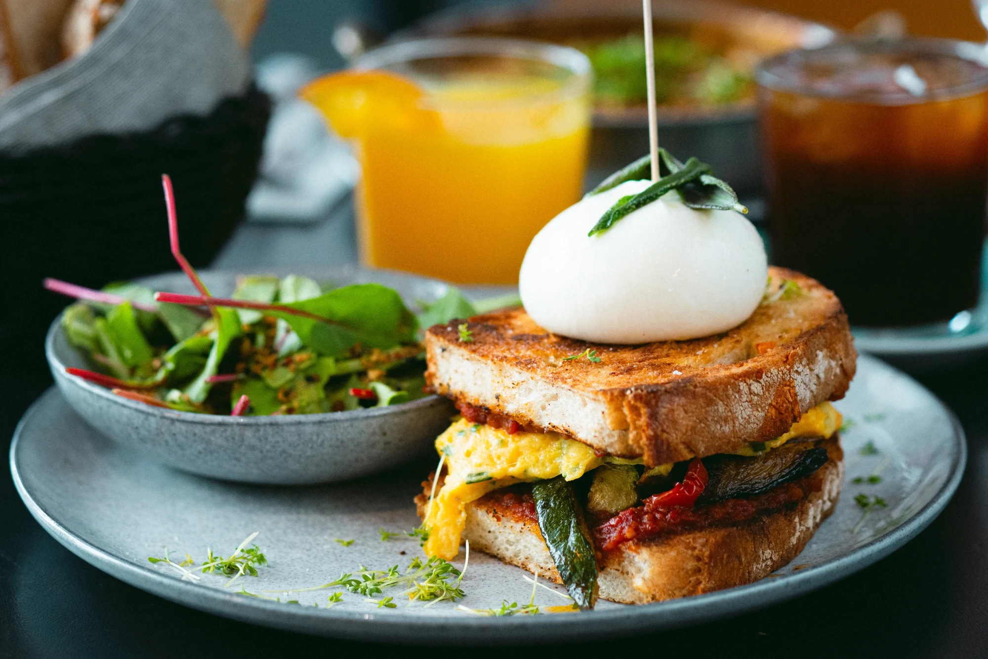 Sandwich mit pochiertem Ei und Beilagensalat, dazu Orangensaft