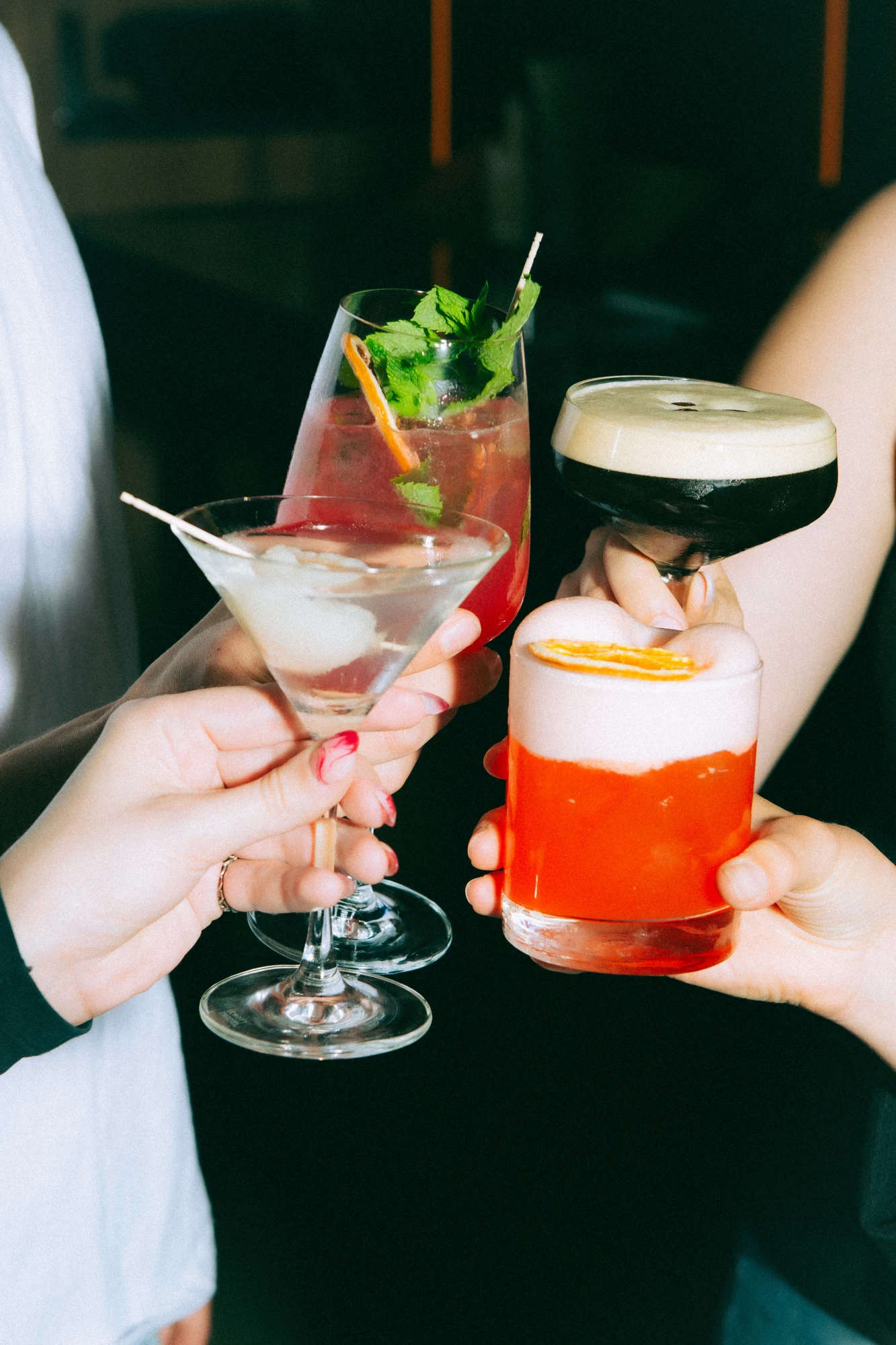 Drei Gäste stoßen mit Cocktails an